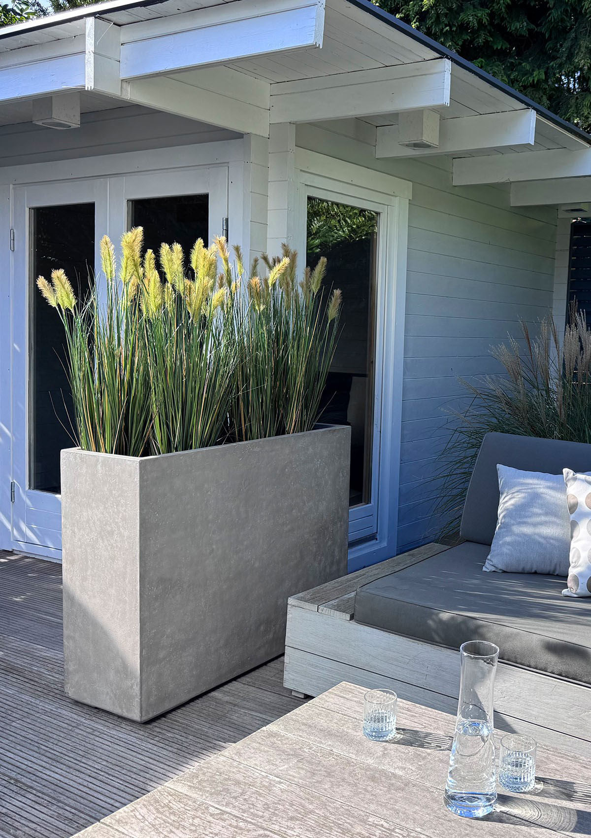 Roccastone Raumteiler mit Gräsern auf Holzdeck