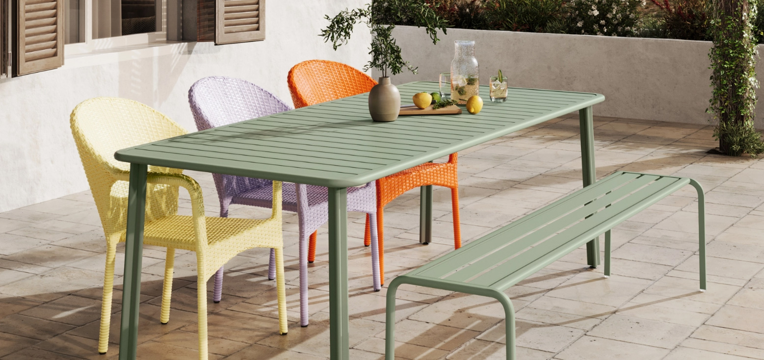 Full of Colours – salbeigrüner Tisch mit bunten Stühlen auf Steinterrasse